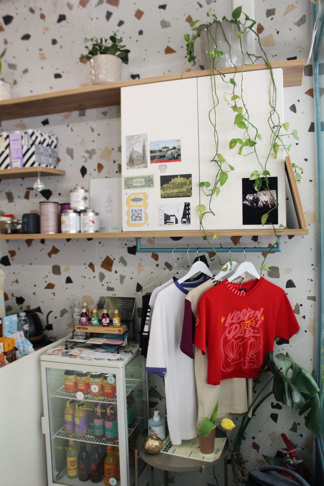 Terrazzo corner with plants, zines and the merch rail